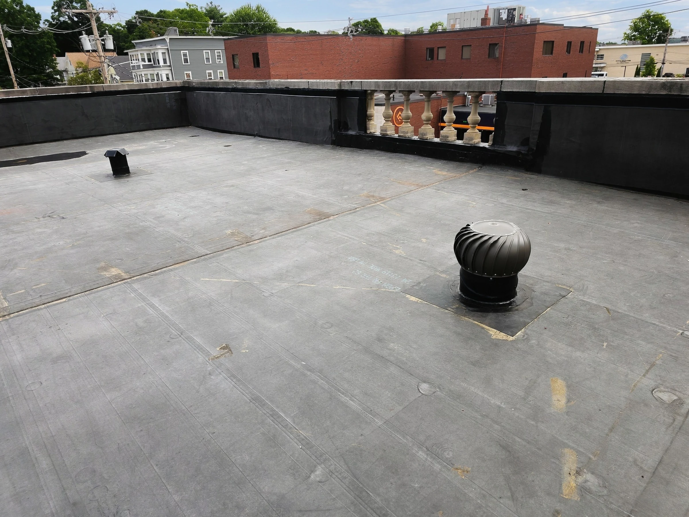 Wide view of a flat roof with a turbine vent and perimeter wall.